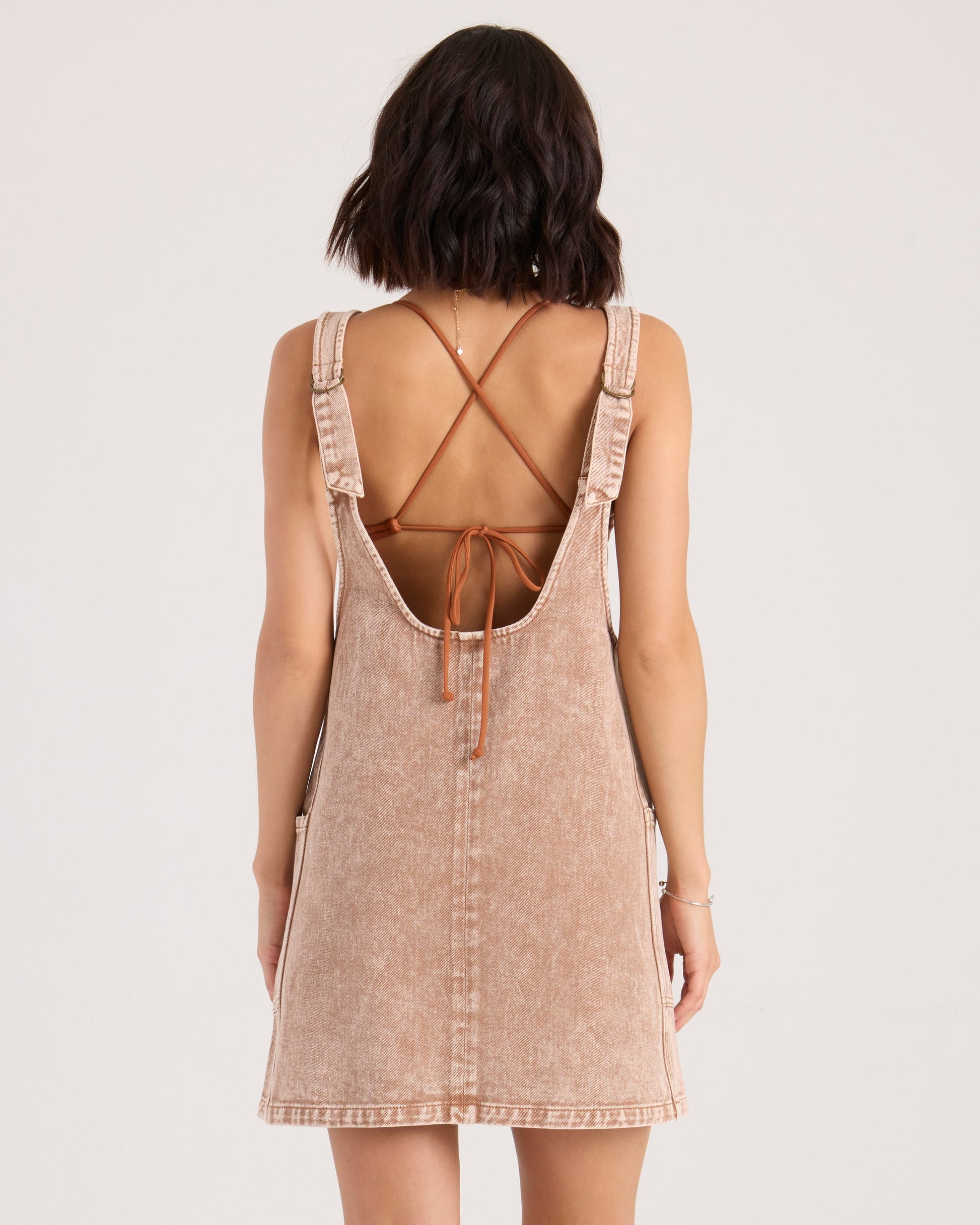 Back view of woman wearing Volcom Ollie Dress in henna color with open back design
