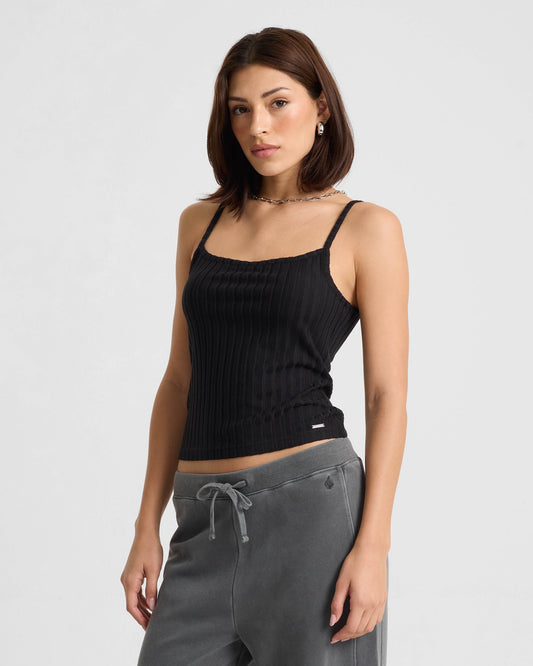 Woman wearing black ribbed tank top with gray sweatpants in studio photo