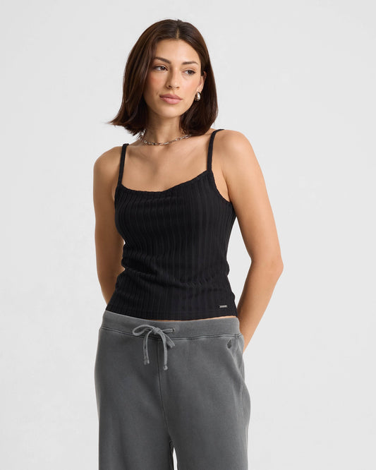 Woman wearing black ribbed tank top with gray sweatpants against white background