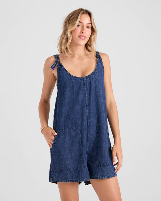 Woman wearing Volcom Lived In Short Romper in medium blue denim with tie straps