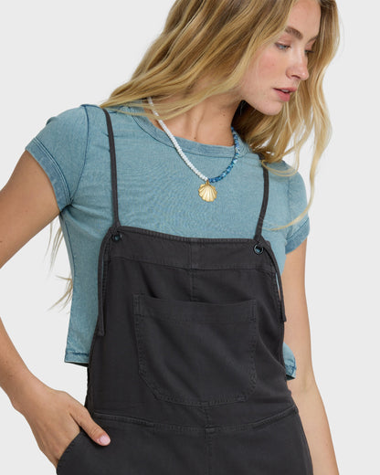 Billabong Wild Pursuit Overall Solid in Off Black worn over blue tee with shell necklace