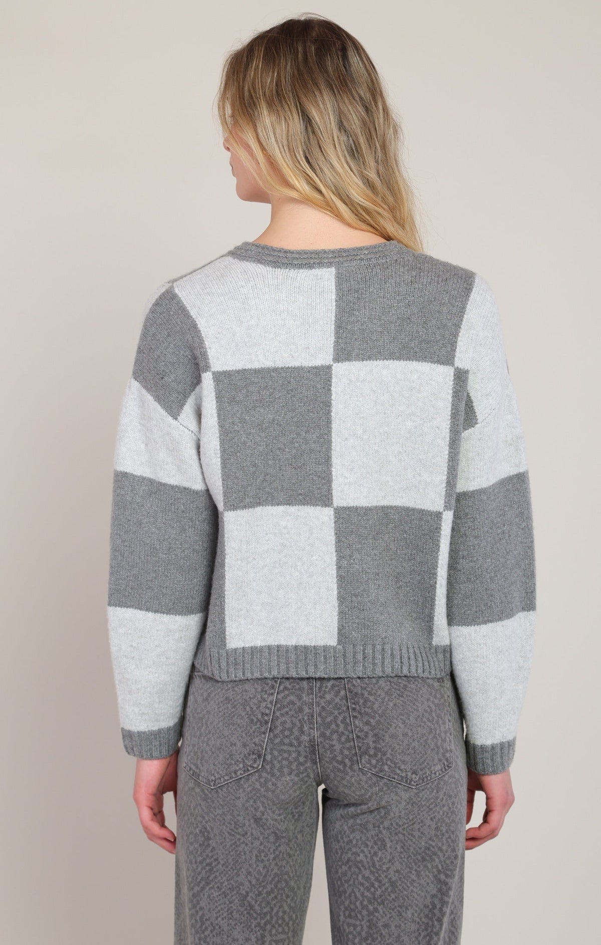 Back view of Dex heather grey colorblock checkered knit sweater with grey jeans