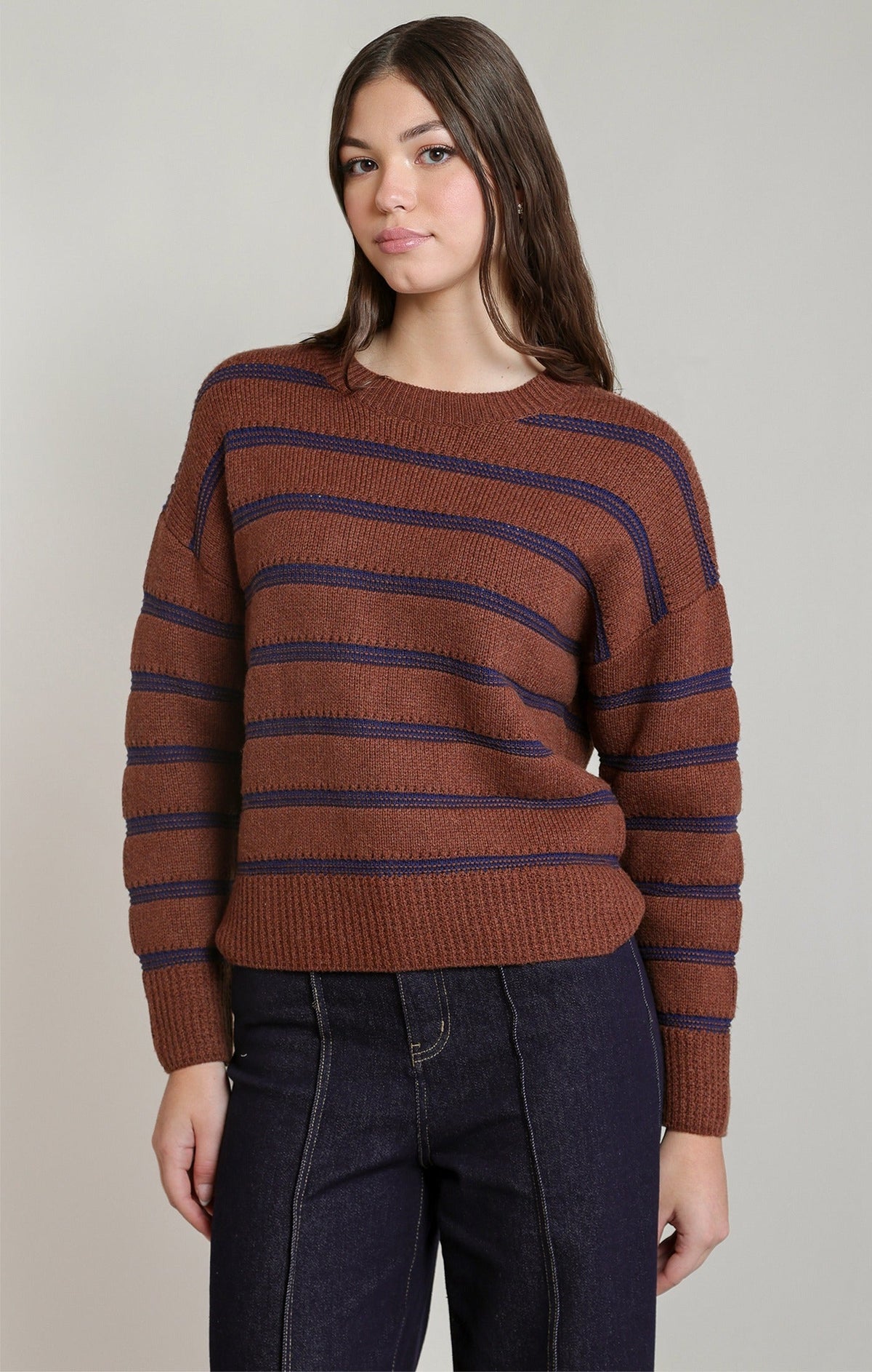 Dex stripe crewneck sweater in rusty brown with navy blue stripes, paired with dark jeans