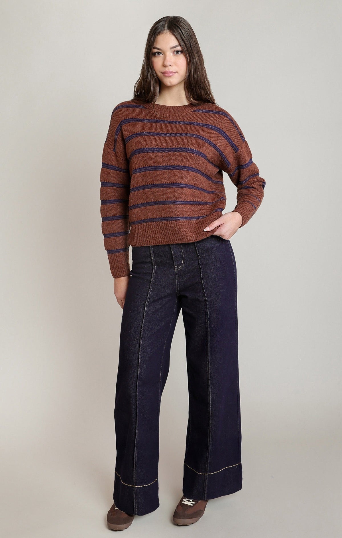 Dex stripe crewneck sweater in rusty brown and navy blue, paired with wide-leg dark denim jeans