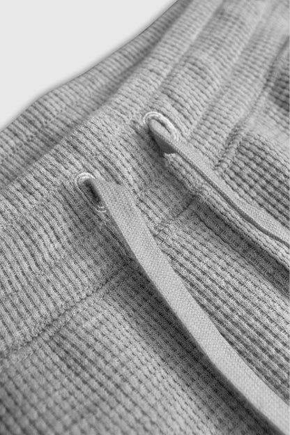 Close-up detail of grey waffle-knit lounge pant waistband with drawstring and eyelets