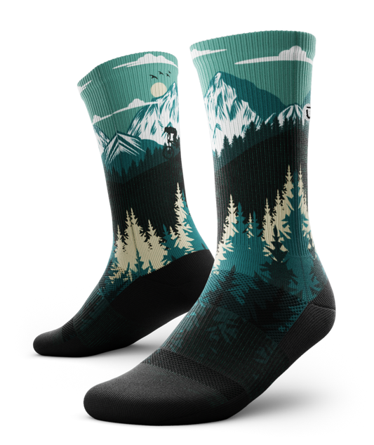 Outway Free Ride Crew Socks featuring teal mountain landscape with pine trees and cyclist silhouette