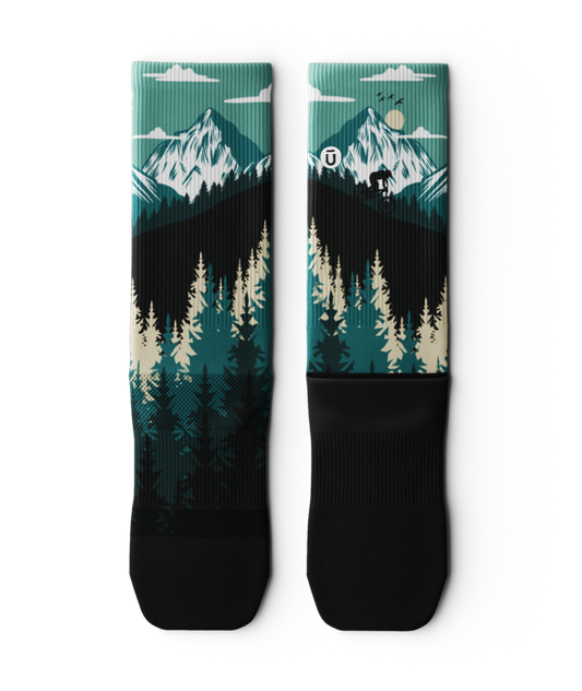 Outway Free Ride Crew Socks featuring teal mountain landscape with pine trees and cyclist silhouette on black base