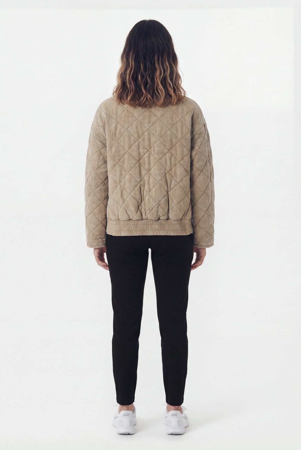 Back view of quilted khaki bomber jacket with black leggings and white Nike sneakers