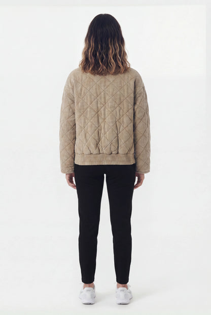 Back view of quilted khaki bomber jacket with black leggings and white Nike sneakers