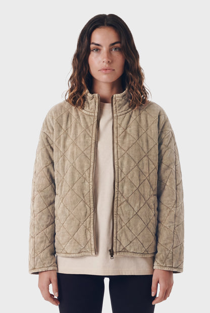Woman wearing TeamLTD Northway Quilted Jacket in washed khaki with diamond quilting pattern