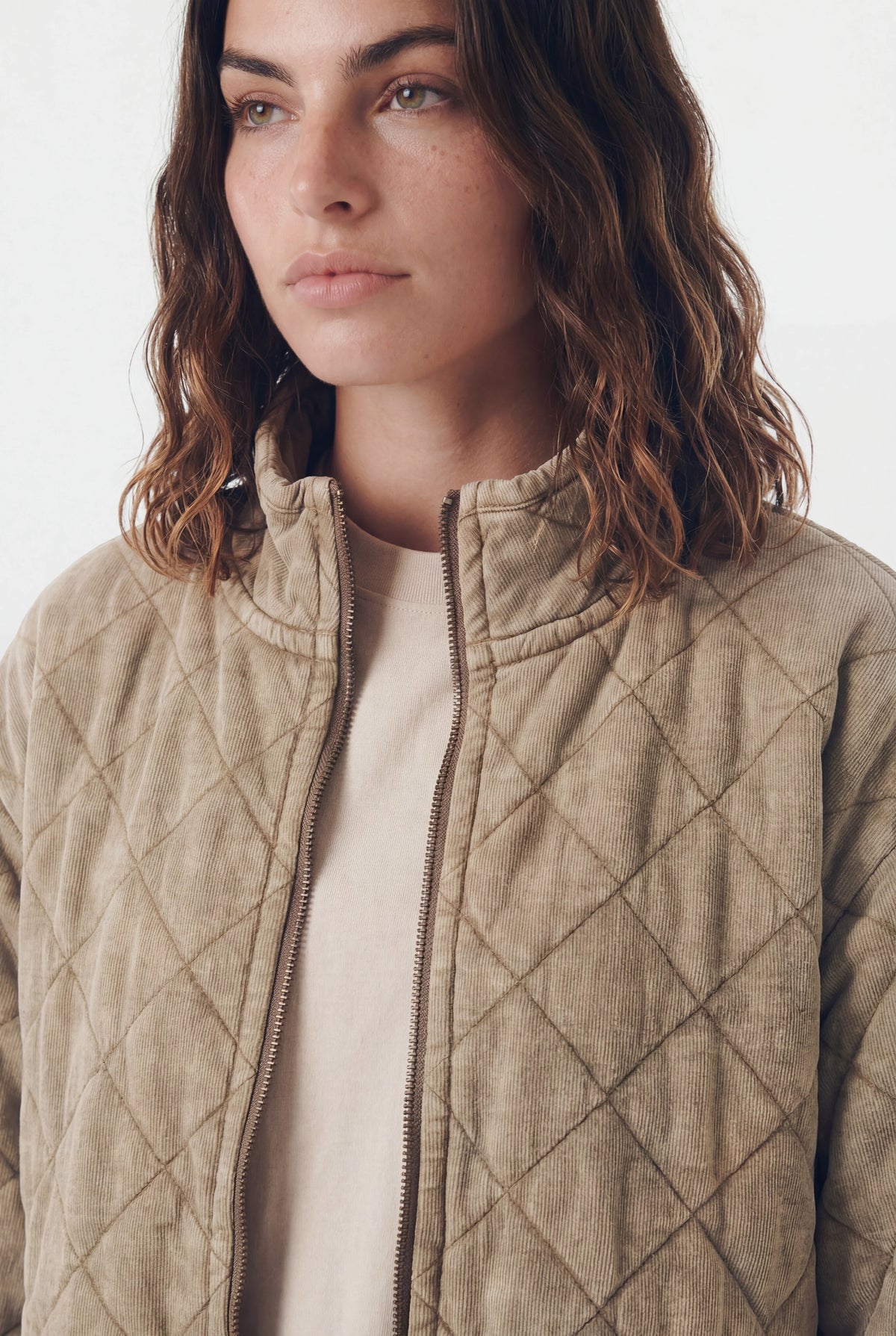 Woman wearing a washed khaki quilted corduroy zip-up jacket with stand collar