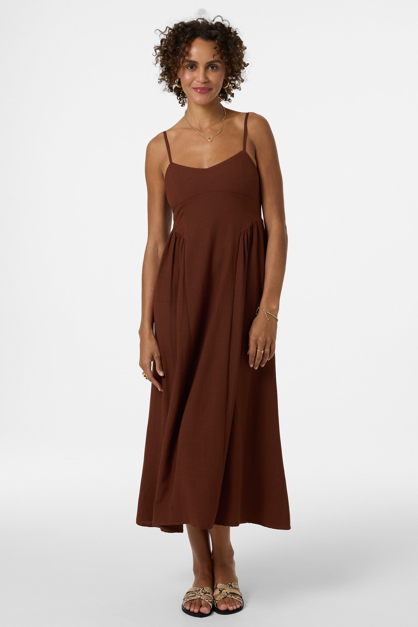 Woman wearing brown midi dress with thin straps and gathered waist