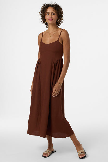 Woman wearing brown sleeveless midi dress with spaghetti straps and flowing silhouette