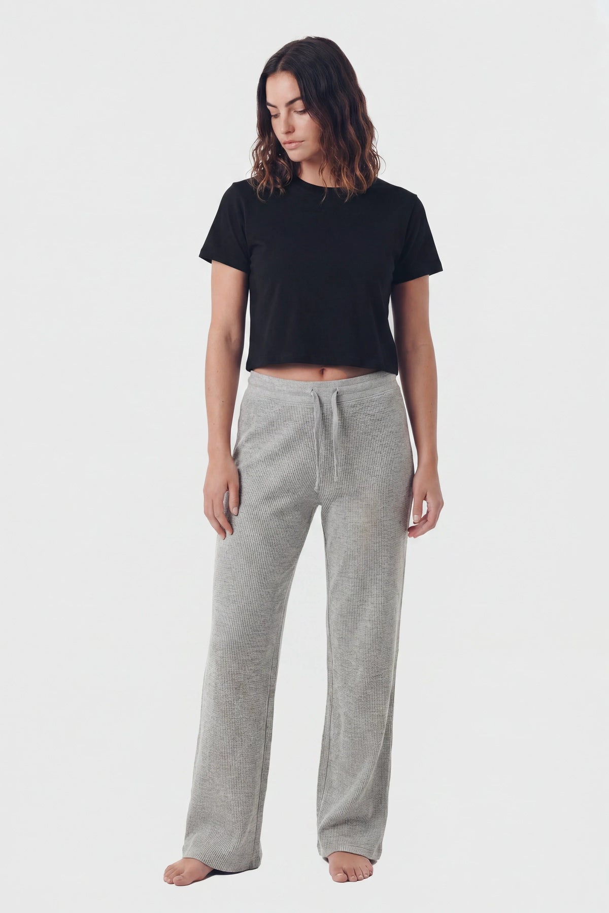 Woman wearing grey waffle knit lounge pants with drawstring waist and black crop top