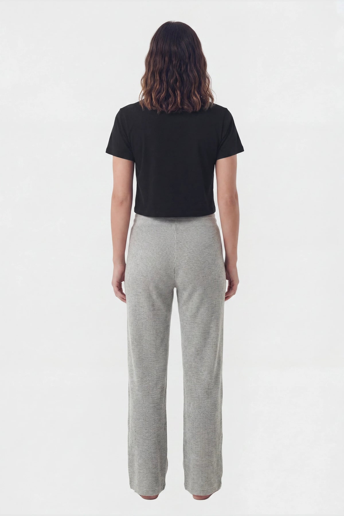 Back view of model wearing grey waffle knit lounge pants with black crop top