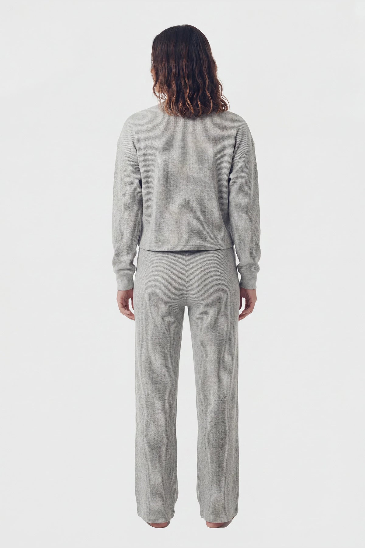 Model wearing grey waffle-knit lounge pants and matching top, back view