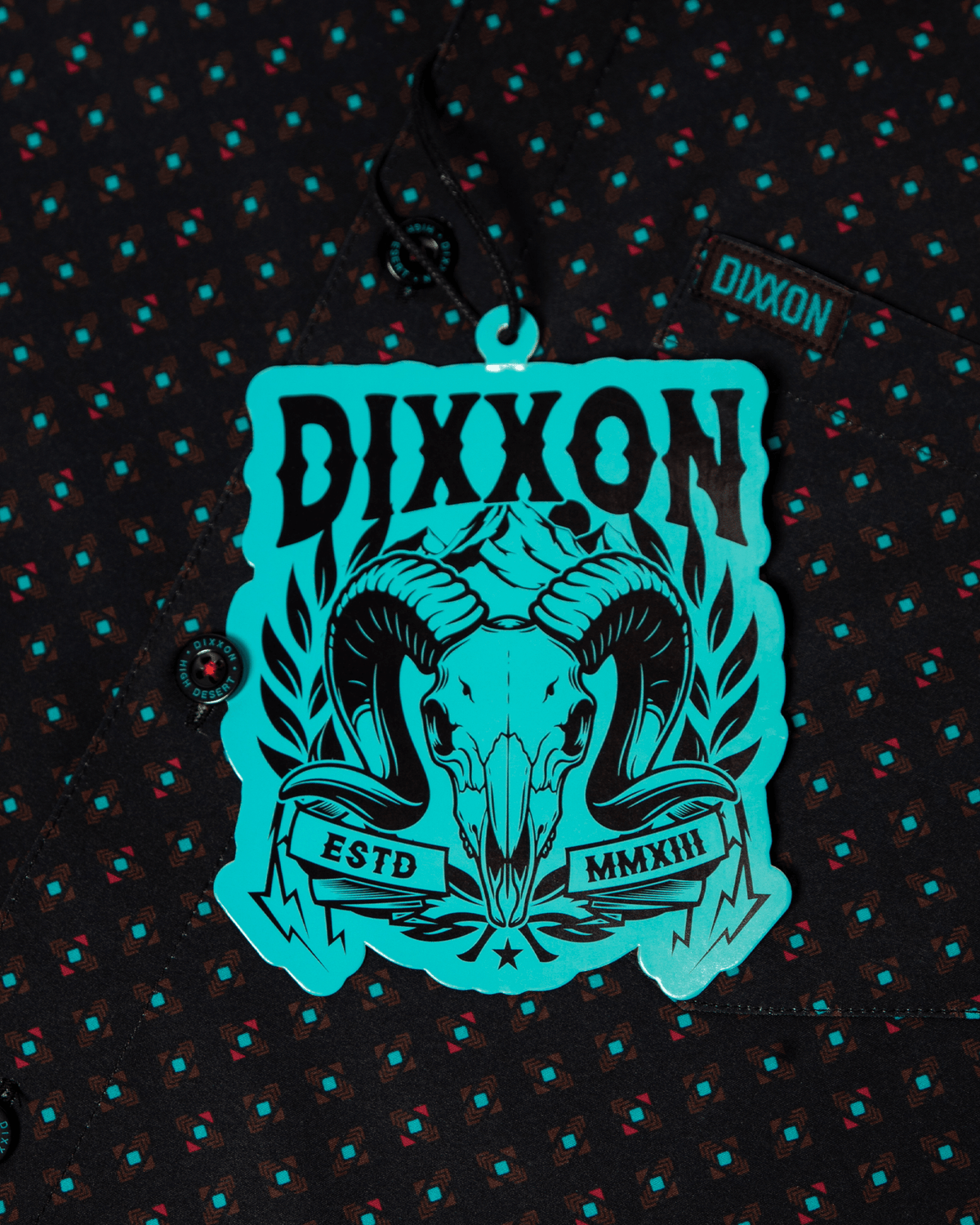 Dixxon High Desert Party Shirt in black with teal geometric pattern and branded hang tag