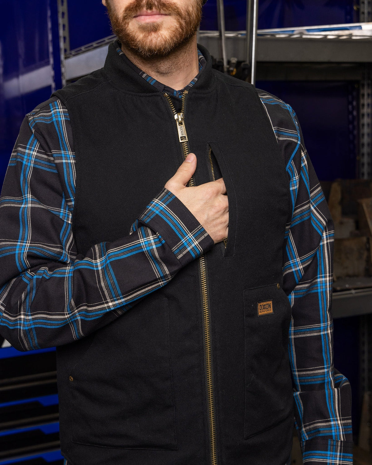 Dixxon Outlaw Work Vest in black with gold zipper, worn over blue plaid flannel shirt