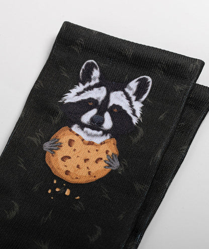 Black crew sock featuring illustrated raccoon holding a large chocolate chip cookie